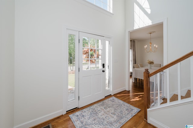 foyer with hardwood / wood-style flooring, a notable chandelier, a towering ceiling, and a wealth of natural light