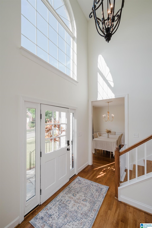 foyer featuring a towering ceiling, wood-type flooring, and a chandelier