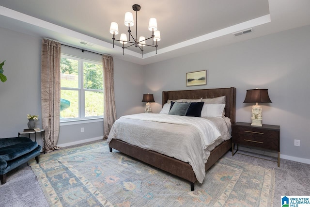 carpeted bedroom with a raised ceiling and a notable chandelier