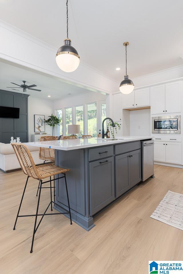 kitchen with gray cabinets, appliances with stainless steel finishes, white cabinetry, an island with sink, and hanging light fixtures