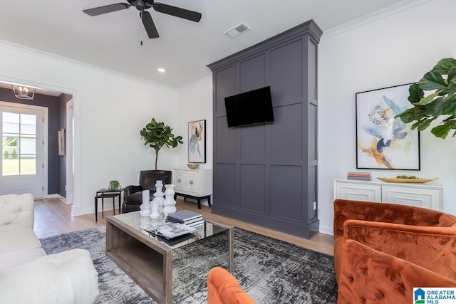 living room with hardwood / wood-style floors, ceiling fan with notable chandelier, and ornamental molding