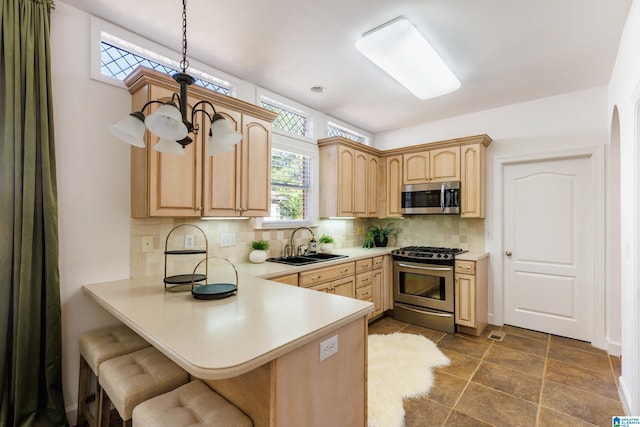 kitchen with stainless steel appliances, sink, hanging light fixtures, and light brown cabinets