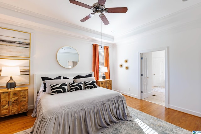 bedroom featuring a tray ceiling, ornamental molding, light hardwood / wood-style floors, and ceiling fan