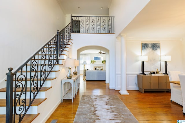 stairway featuring hardwood / wood-style floors, crown molding, decorative columns, and ceiling fan