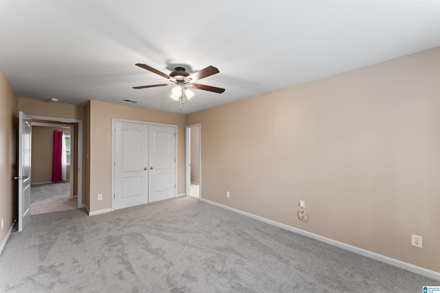 unfurnished bedroom featuring light colored carpet, ceiling fan, and a closet