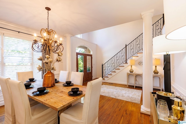 dining room with ornate columns, a wealth of natural light, hardwood / wood-style floors, and an inviting chandelier