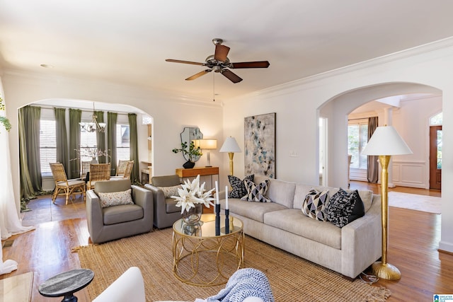 living room with ornamental molding, light hardwood / wood-style floors, and ceiling fan