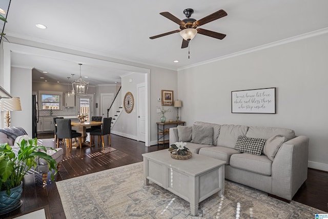 living room with crown molding, dark wood-type flooring, and ceiling fan with notable chandelier