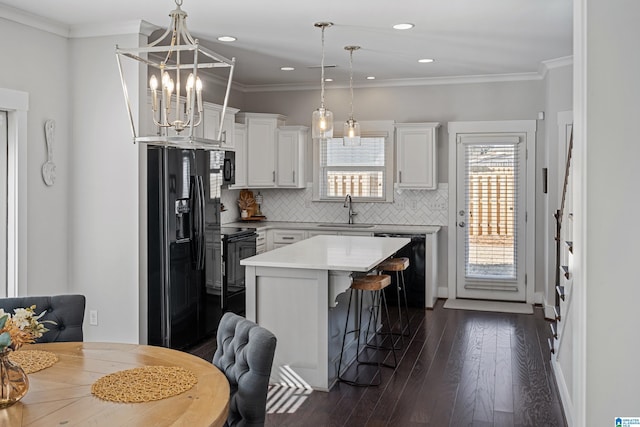 kitchen with a kitchen island, sink, white cabinets, hanging light fixtures, and black appliances