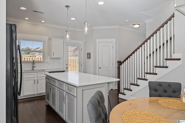 kitchen featuring sink, black fridge, a center island, decorative backsplash, and white cabinets