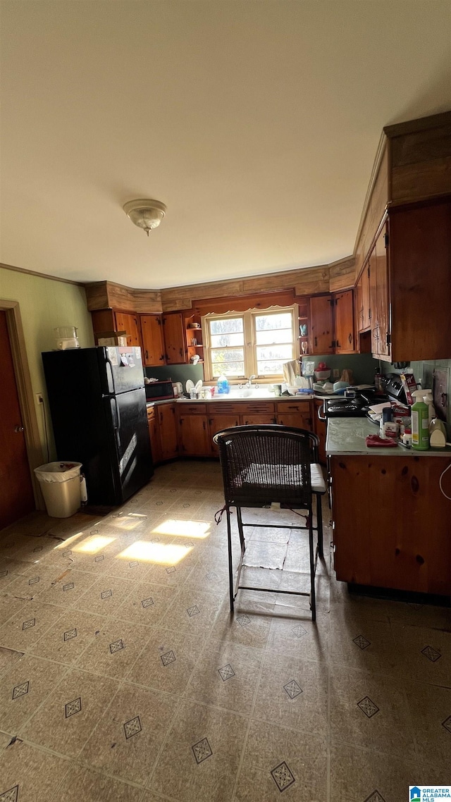 kitchen with ornamental molding and black fridge