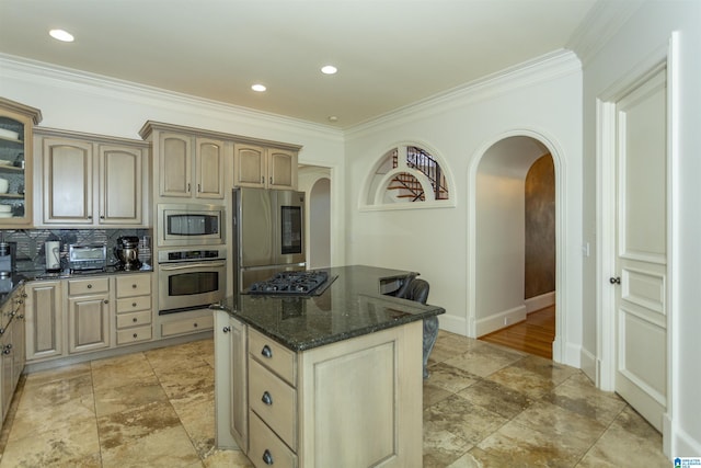 kitchen with dark stone countertops, light brown cabinetry, crown molding, and appliances with stainless steel finishes