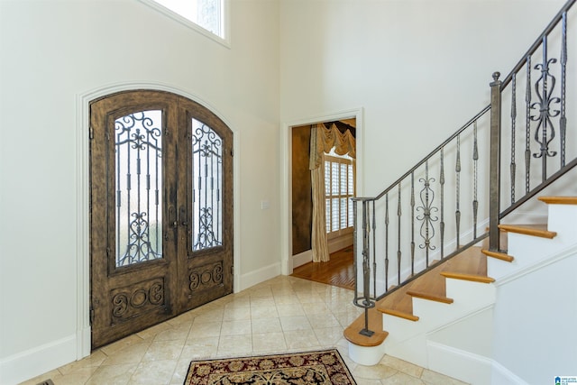 tiled foyer with french doors and a high ceiling