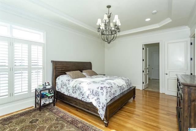 bedroom with crown molding, an inviting chandelier, and hardwood / wood-style floors