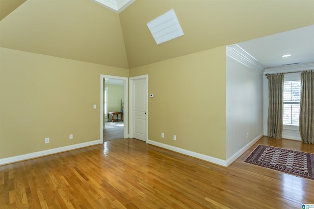 unfurnished room featuring crown molding, a skylight, high vaulted ceiling, and light wood-type flooring