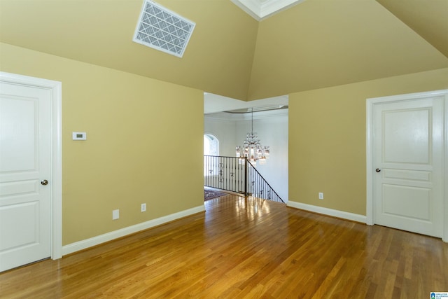 unfurnished room featuring wood-type flooring, a notable chandelier, and high vaulted ceiling