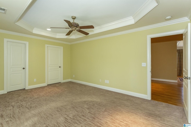 unfurnished bedroom featuring ornamental molding, light colored carpet, ceiling fan, and a tray ceiling