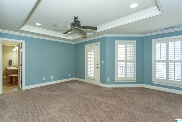 empty room with a raised ceiling, crown molding, carpet, and ceiling fan