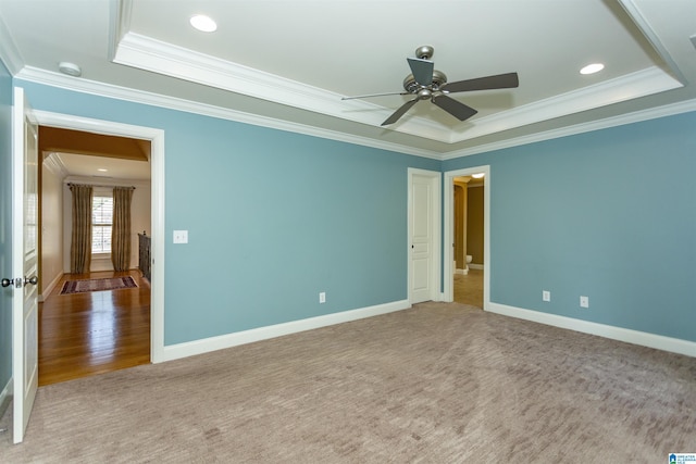 carpeted empty room featuring a raised ceiling, ornamental molding, and ceiling fan