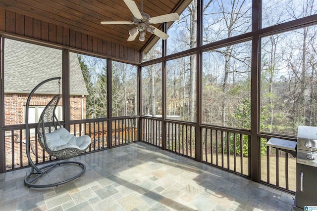 unfurnished sunroom with vaulted ceiling, a wealth of natural light, wooden ceiling, and ceiling fan