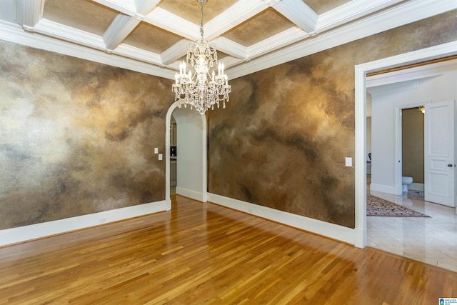 empty room featuring crown molding, wood-type flooring, coffered ceiling, and beam ceiling