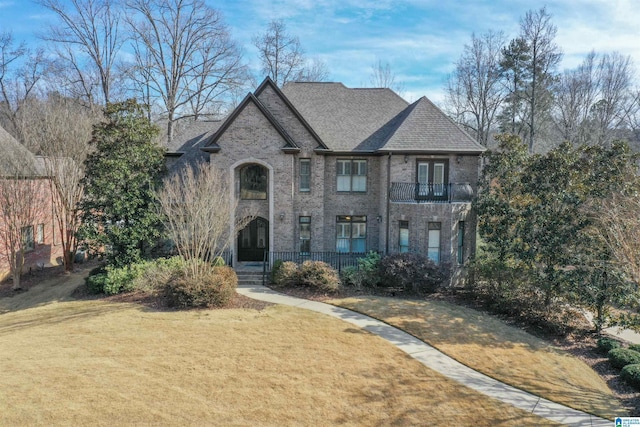 view of front of home with a balcony and a front yard