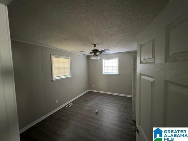 empty room with ceiling fan, dark wood-type flooring, and a textured ceiling