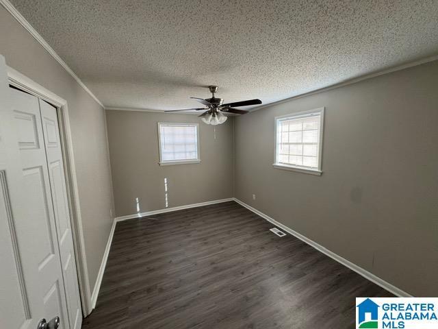 unfurnished bedroom with crown molding, ceiling fan, a textured ceiling, and dark hardwood / wood-style flooring