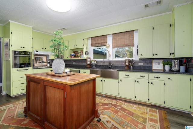 kitchen featuring sink, a center island, ornamental molding, dark hardwood / wood-style flooring, and oven