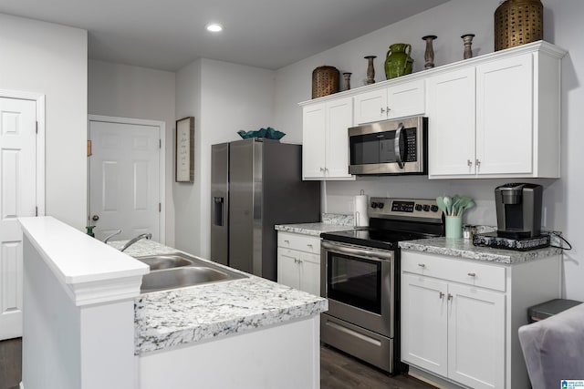 kitchen with appliances with stainless steel finishes, dark hardwood / wood-style floors, an island with sink, sink, and white cabinets