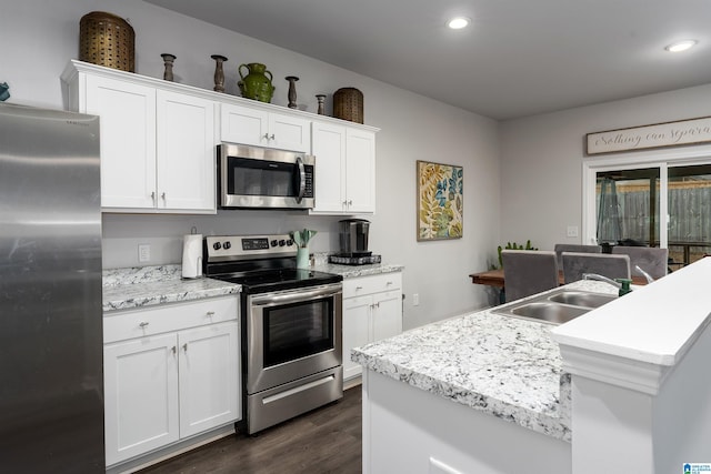 kitchen featuring sink, dark hardwood / wood-style floors, an island with sink, stainless steel appliances, and white cabinets