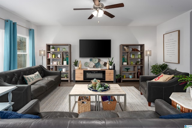 living room featuring dark wood-type flooring, ceiling fan, and a premium fireplace