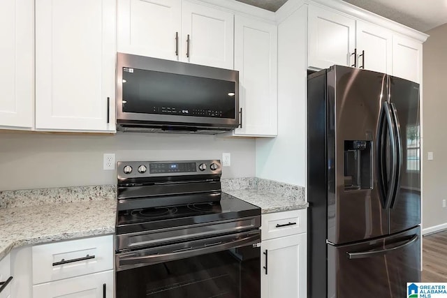 kitchen featuring appliances with stainless steel finishes, hardwood / wood-style floors, white cabinets, and light stone counters