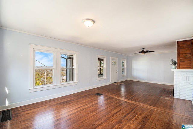 unfurnished living room featuring dark wood-type flooring, ceiling fan, ornamental molding, and a wealth of natural light