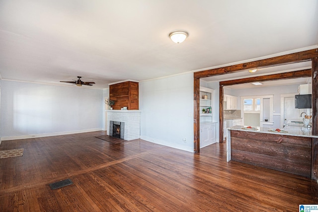 unfurnished living room with ceiling fan, dark hardwood / wood-style floors, and a fireplace