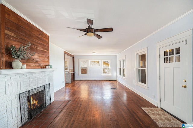 unfurnished living room featuring ornamental molding, a brick fireplace, dark hardwood / wood-style floors, and ceiling fan