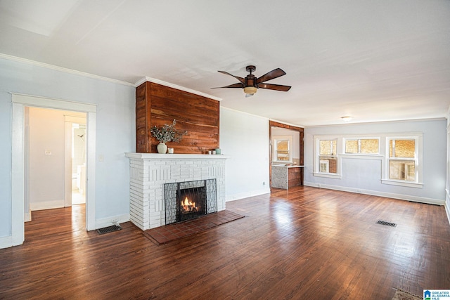 unfurnished living room featuring crown molding, dark wood-type flooring, a fireplace, and ceiling fan