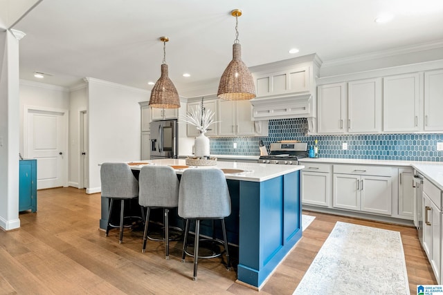 kitchen featuring white cabinetry, stainless steel appliances, decorative light fixtures, and a kitchen island