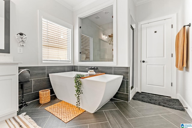 bathroom with tile walls, vanity, crown molding, and plus walk in shower