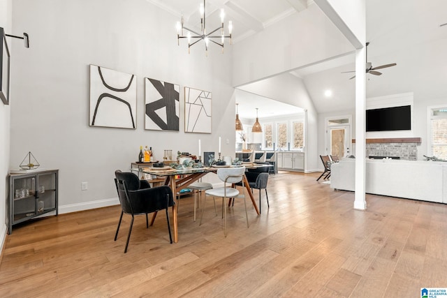 dining space with light hardwood / wood-style flooring, beam ceiling, a high ceiling, ornamental molding, and ceiling fan with notable chandelier