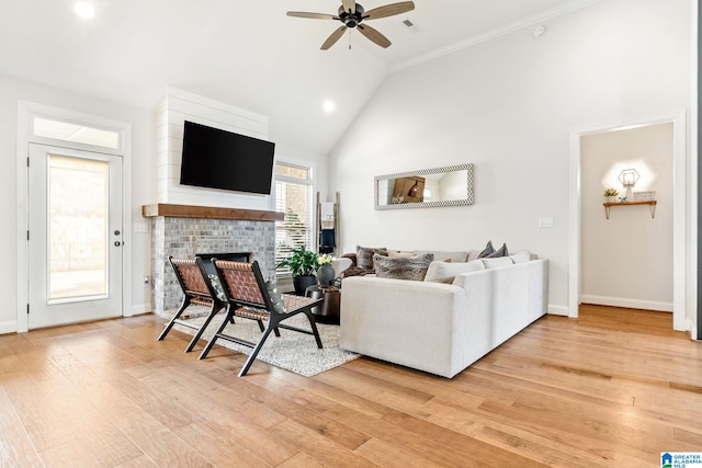 living room featuring hardwood / wood-style flooring, ceiling fan, a brick fireplace, and high vaulted ceiling