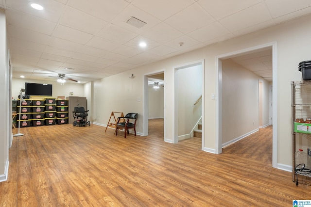 living area with hardwood / wood-style flooring, a paneled ceiling, and ceiling fan