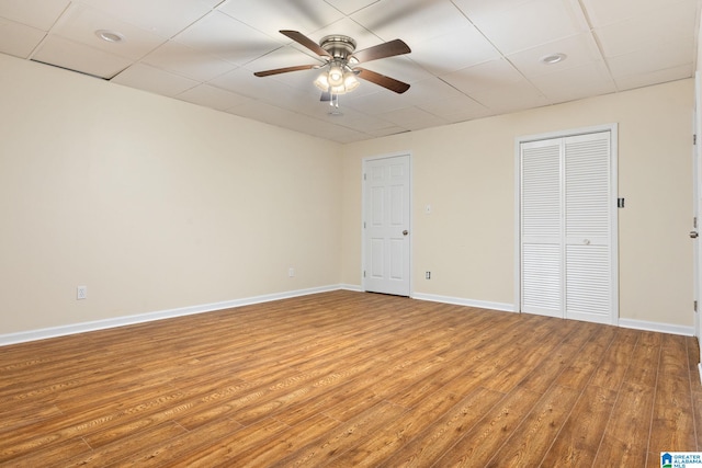 interior space featuring a drop ceiling, hardwood / wood-style flooring, and ceiling fan