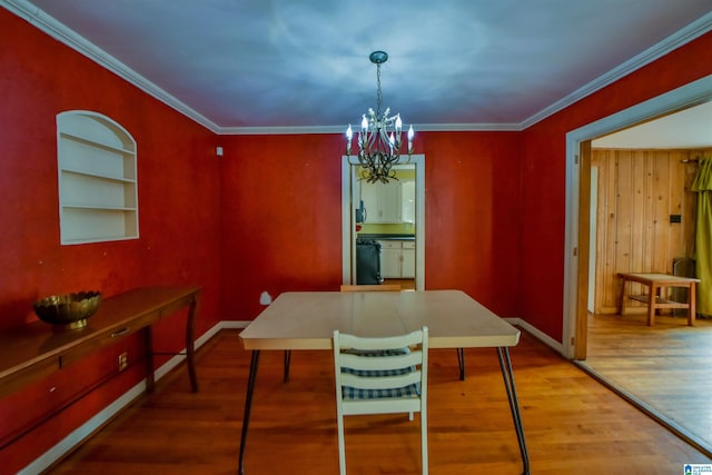 dining room featuring an inviting chandelier, built in shelves, ornamental molding, and hardwood / wood-style flooring