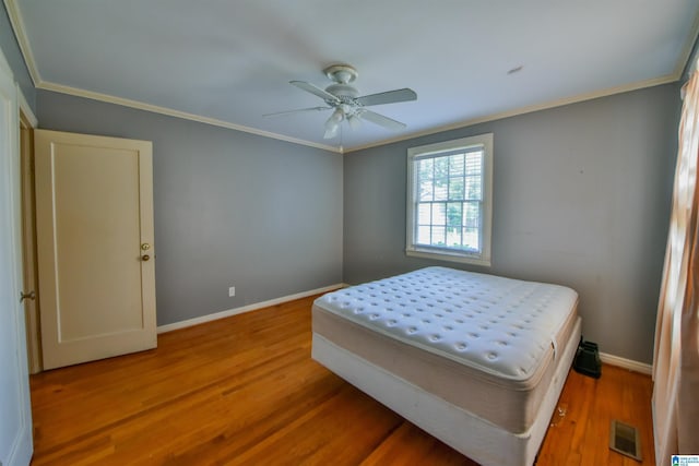 bedroom featuring hardwood / wood-style flooring, crown molding, and ceiling fan