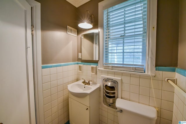 bathroom featuring vanity, toilet, and tile walls