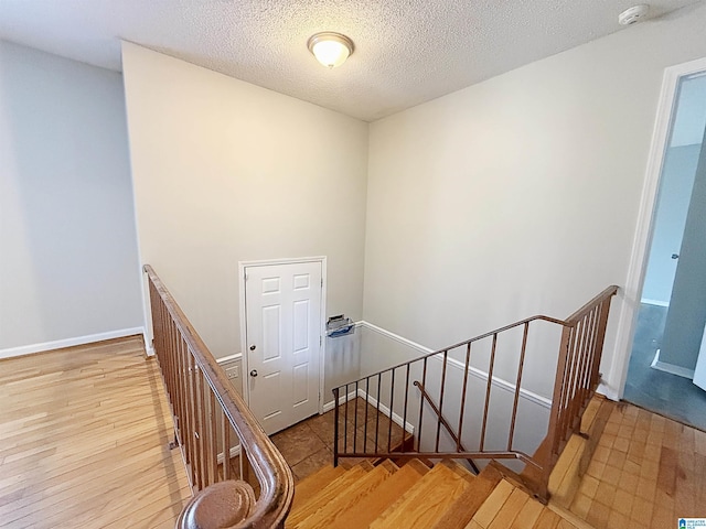 stairs featuring wood-type flooring and a textured ceiling