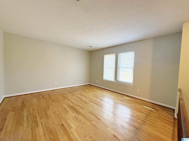 unfurnished room featuring a textured ceiling and light wood-type flooring