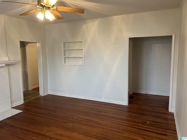 empty room featuring dark hardwood / wood-style flooring, a fireplace, ceiling fan, and built in shelves