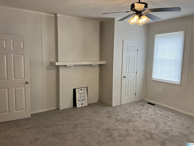 unfurnished living room featuring ceiling fan, plenty of natural light, a fireplace, and light carpet